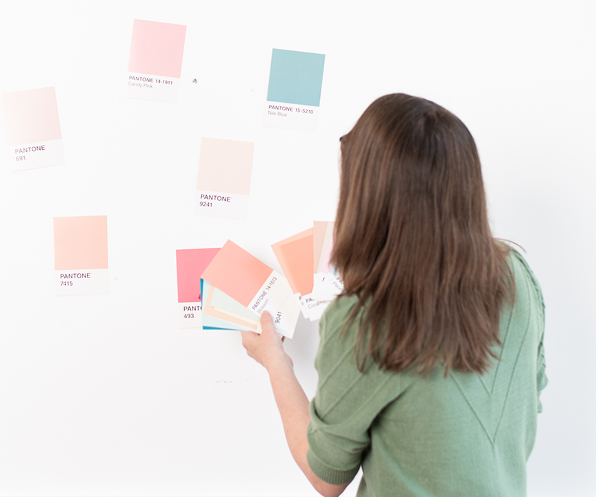 Andrea building a brand palette while looking at a wall with Pantone colour samples on it